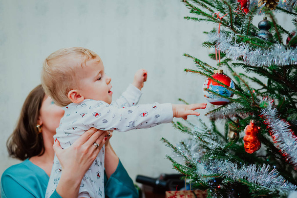 portrait of little baby boy in Santa hat on Christmas tree light background  - Fotó, kép
