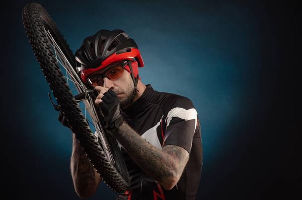парень-велосипедист в велосипедном шлеме с велосипедным колесом
 - Фото, изображение