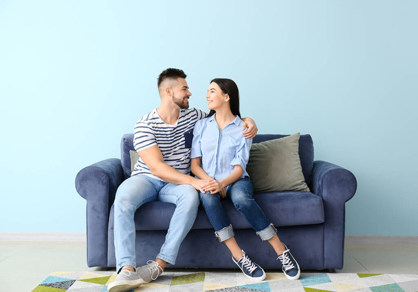 Young couple sitting on sofa at home - Fotó, kép