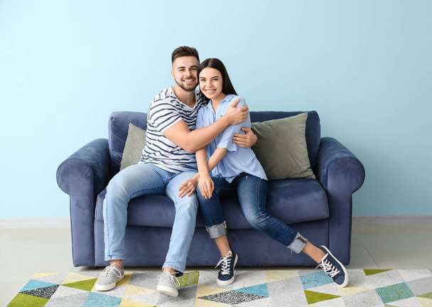 Young couple sitting on sofa at home - Fotografie, Obrázek