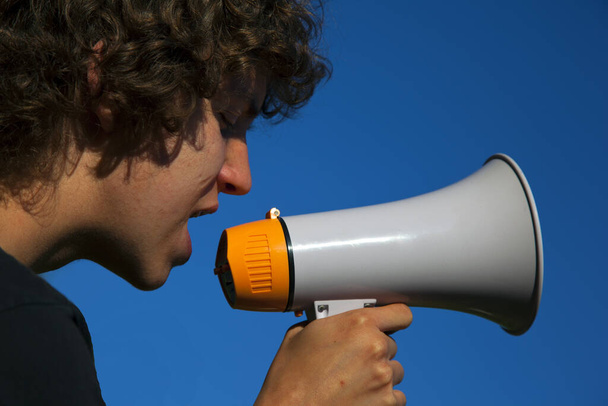 a toung boy shouts in a megaphone - Foto, Imagen