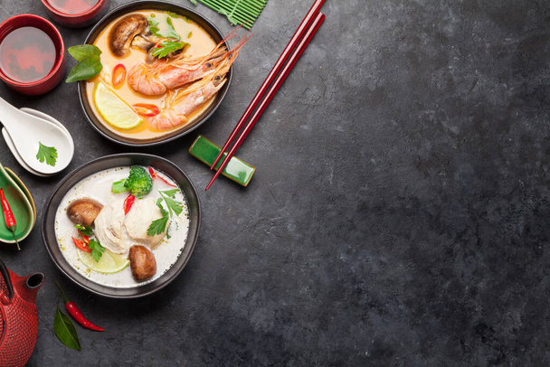 Soupes thaïlandaises traditionnelles Tom Yum et Tom Kha avec fruits de mer, poulet, champignons, lait de coco et épices chaudes. Avec théière verte et bol. Vue supérieure avec espace de copie
 - Photo, image