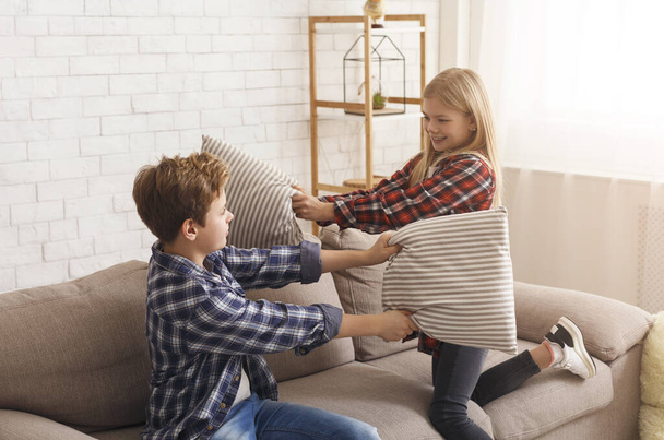 Мальчик и девочка веселятся, дерутся с подушками дома
 - Фото, изображение