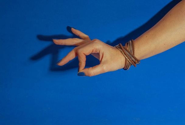female hand with blue nails showing ok sign on blue background - Zdjęcie, obraz