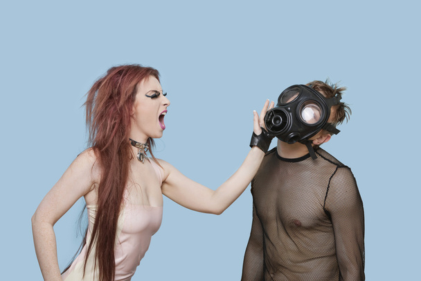 Funky woman slapping man in gas mask - Foto, Imagen