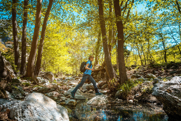 Woman hiking jumping over a creek in spring - Foto, imagen