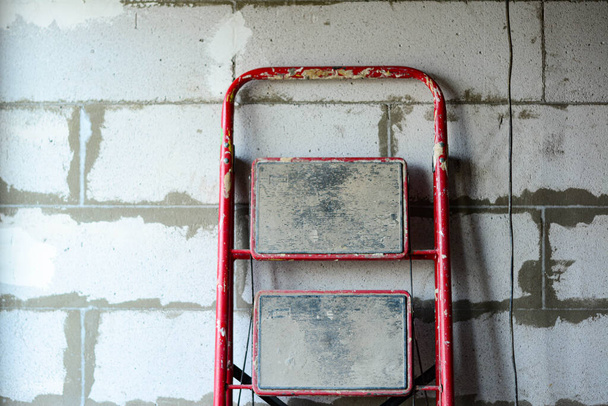 Scala rossa sullo sfondo di un muro di blocchi di cemento armato
 - Foto, immagini