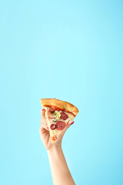 Female hand with slice of tasty pizza on color background - Photo, Image