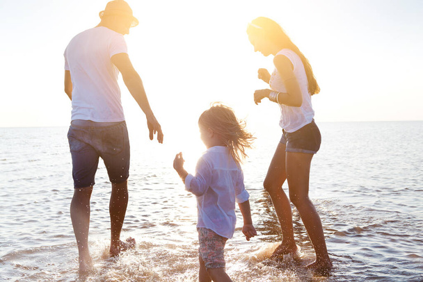 Onnellinen perhe kävelee merivedessä
 - Valokuva, kuva