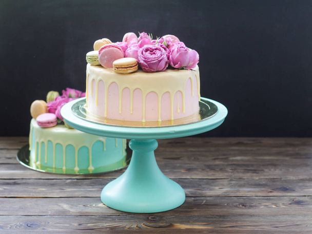 Pink, ivory and turquoise cake with melted white chocolate, fresh roses and french macaroons   - Photo, Image