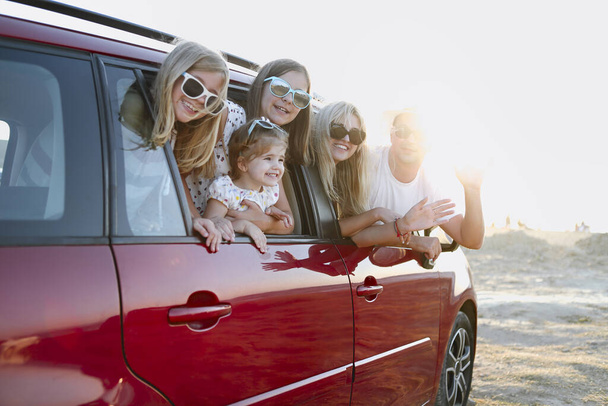 Feliz familia sonriente con hijas en el coche con fondo de mar
 - Foto, imagen