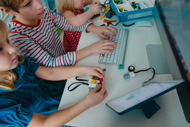 παιδιά που κατασκευάζουν ρομπότ και το προγραμματίζουν με touch pad και υπολογιστή - Φωτογραφία, εικόνα