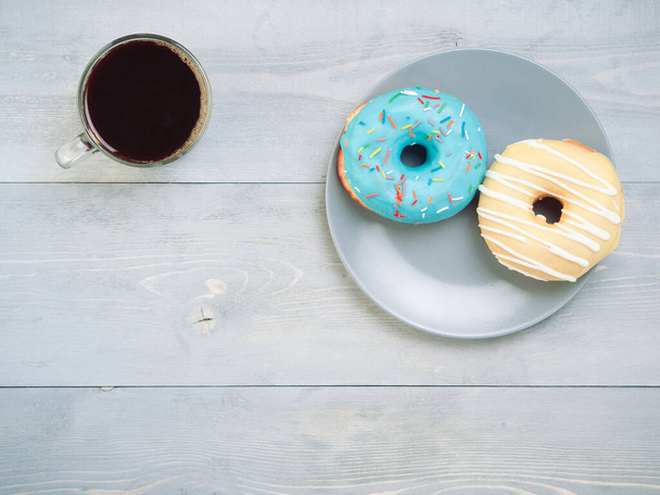 Top view of assorted donuts and coffee on gray wooden background with copy space. Various glazed doughnuts with sprinkles on grey wooden table. Smile sign, good morning concept - Photo, Image
