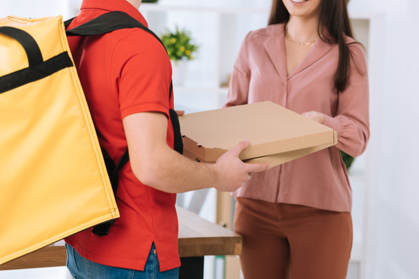 Cropped view of courier with thermo backpack giving pizza boxes to businesswoman  - Fotografie, Obrázek