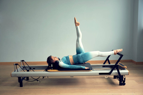 leotard workout pilates training. athletic pilates reformer exercises. pilates machine equipment. young asian woman pilates stretching sport in reformer bed instructor girl in a studio - Foto, Imagen