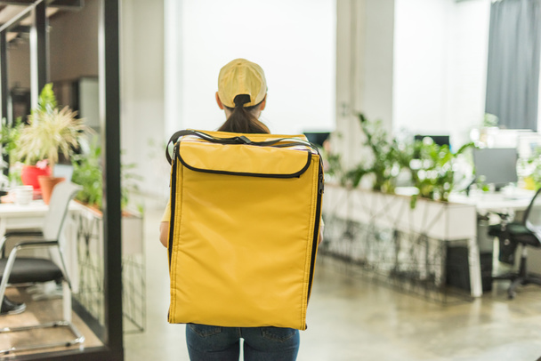 Back view of courier with thermo backpack standing in office - Fotó, kép