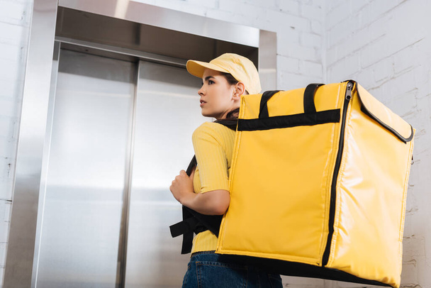 Back view of courier with thermo backpack standing near elevator  - Foto, Imagem
