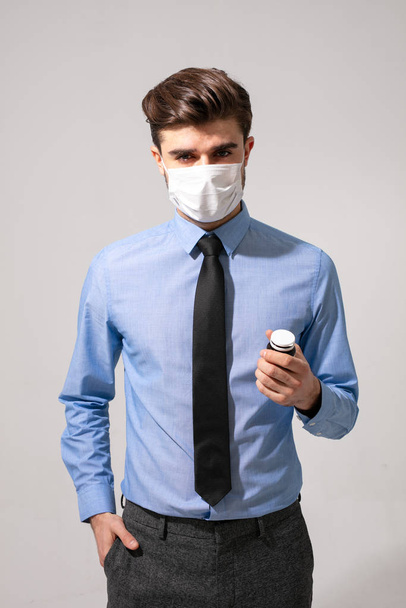 elegant man with tie and mouth protection taking some pills for stress or to prevent getting sick - Foto, Imagem