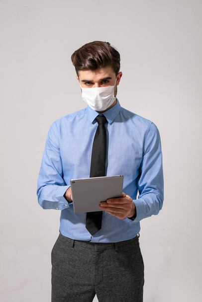 элегантный бизнесмен или медицинский персонал, работающий над таблеткой с маской для лица от заразного вируса
 - Фото, изображение