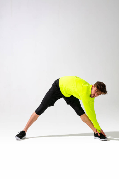 doing stretching first. young man in sportwear training and stretching his muscle on white background - 写真・画像