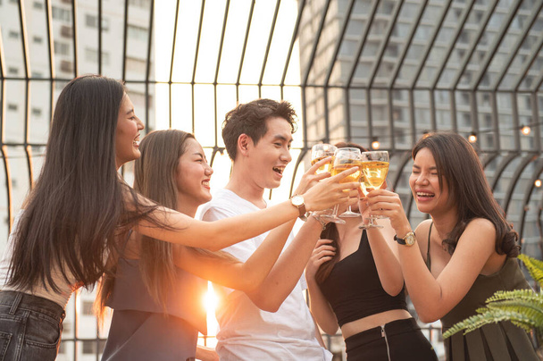 Group of asian multiple gender holding glass of wine chat together with friends while celebrating dance party on outdoor rooftop nightclub,leisure lifestyle of young friendship enjoyment concept. - Photo, Image