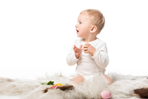 niedliches Kind mit offenem Mund, das auf Fell wegsieht, isoliert auf weißem - Foto, Bild