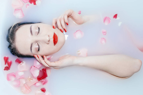 Молода сексуальна дівчина приймає молочну ванну з пелюстками троянд
 - Фото, зображення