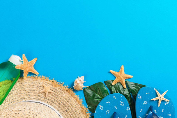 Plážové příslušenství se slaměnou čapkou a mušlí na modrém pozadí s prostorem pro kopírování - Fotografie, Obrázek