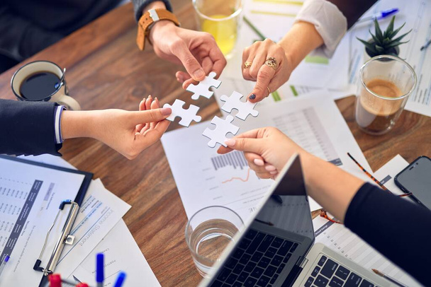 Group of business workers with hands together connecting pieces of puzzle at the office - Photo, Image