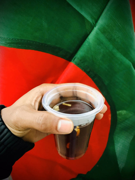 červený čaj, Lal cha, silný ča, červený čaj v jednorázové sklenici, v ruce proti barvě červené a zelené. - Fotografie, Obrázek