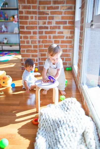Красиві малюки грають навколо багатьох іграшок в дитячому саду
 - Фото, зображення