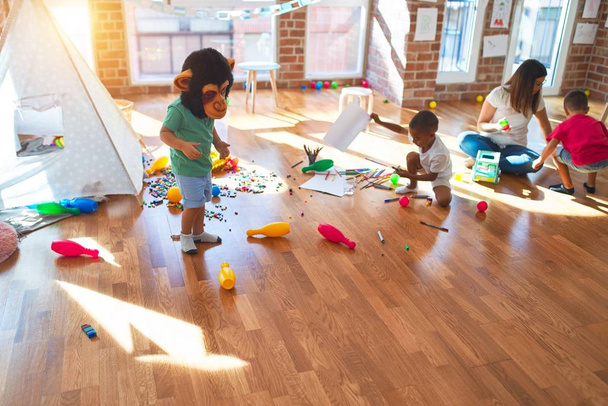 Jeune belle enseignante et tout-petits jouant autour de beaucoup de jouets à la maternelle
 - Photo, image