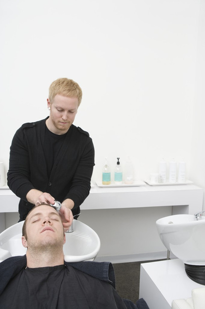 Male client has hair shampooed in unisex hair salon - Фото, изображение