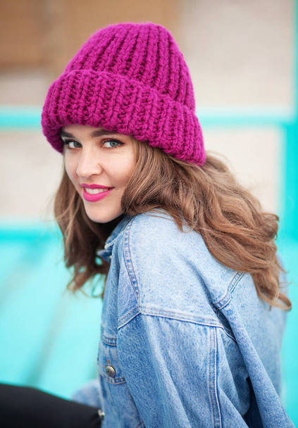 Young beautiful woman in denim jacket and knit hat  - Фото, изображение