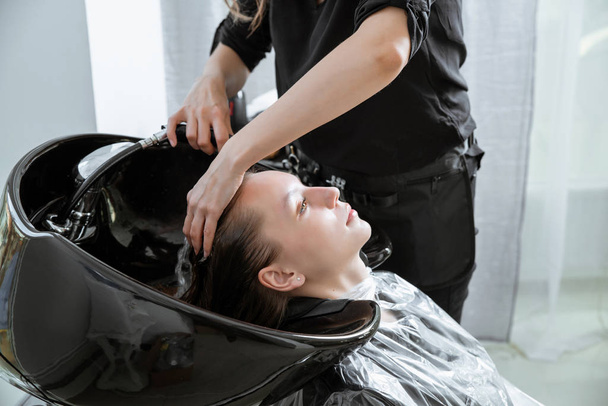 stylista włosów mycie włosów yong blondynka dziewczyna w salonie fryzjerskim przed fryzurą - Zdjęcie, obraz