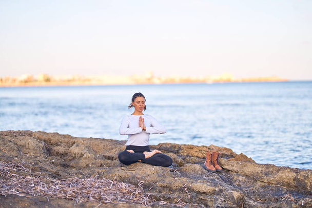 Jonge mooie sportvrouw die yoga beoefent. Coach onderwijs gebed poseren op het strand - Foto, afbeelding
