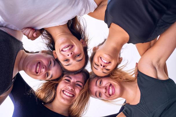 Jonge mooie groep van sportwomen glimlachend gelukkig. Staande knuffelen met een glimlach op het gezicht in de sportschool - Foto, afbeelding
