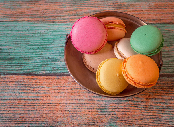 Metal plate with French macarons on a wooden table - Φωτογραφία, εικόνα
