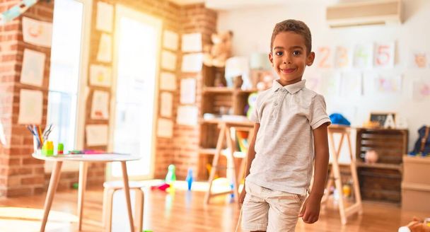 Прекрасний афроамериканець стоїть і посміхається навколо багатьох іграшок у дитячому садку. - Фото, зображення
