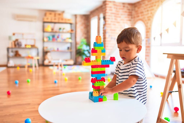 Красивий маленький хлопчик грає з будівельними блоками в дитячому саду
 - Фото, зображення