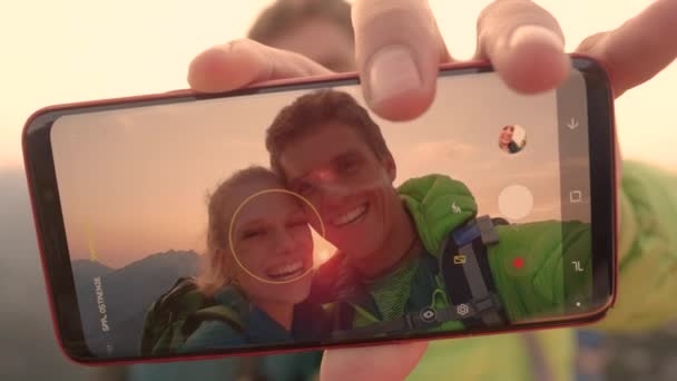 Iloinen mies pitelee älypuhelintaan ottaessaan selfien tyttöystävänsä kanssa.
. - Materiaali, video