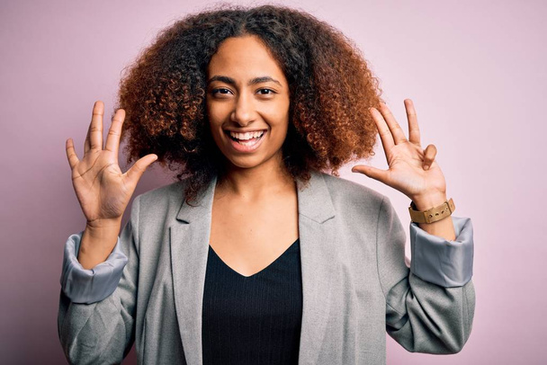 Joven mujer de negocios afroamericana con cabello afro con elegante chaqueta que muestra y señala con los dedos número nueve mientras sonríe confiada y feliz
. - Foto, imagen