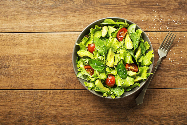 Fresh green lettuce salad with avocado and tomato - Foto, afbeelding