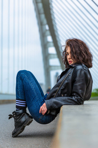 woman in blue jeans and leather jacket on bridge - Photo, image
