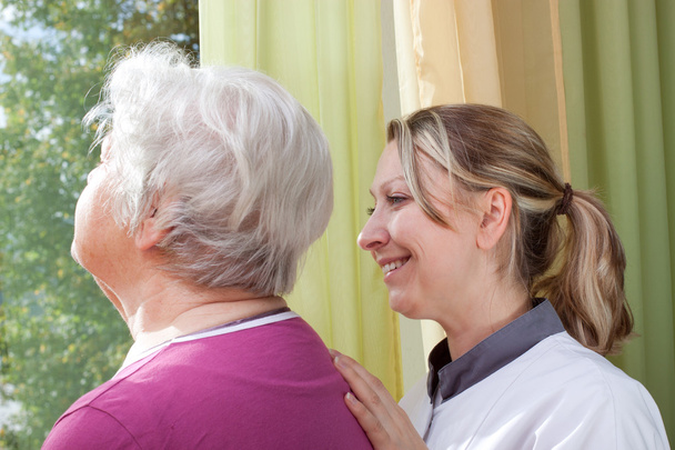 Nurse and old woman standing at the window - Photo, Image