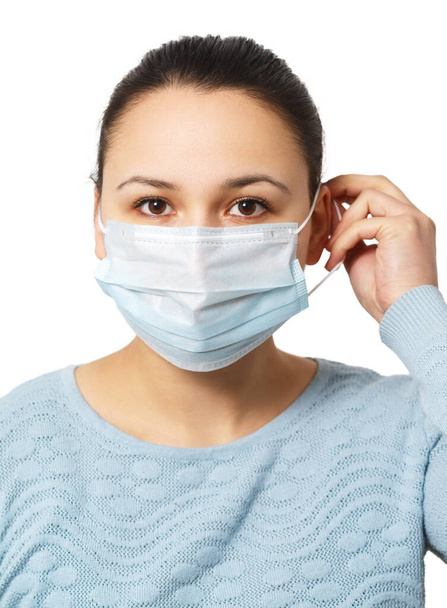 Studio portrait of young woman wearing a face mask, looking at camera, close up, isolated on gray background. Flu epidemic, dust allergy, protection against virus - Fotoğraf, Görsel