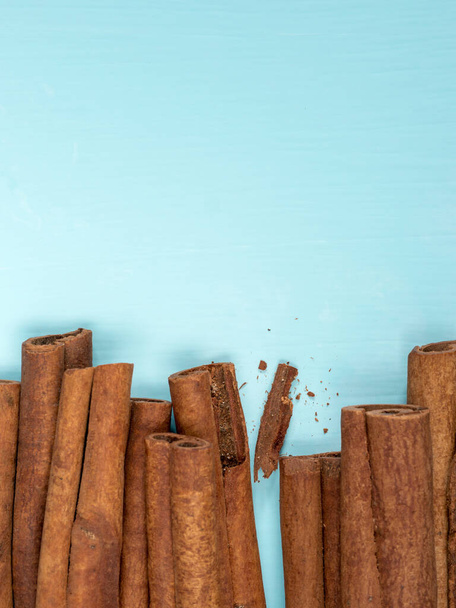 Cinnamon sticks on turquoise blue background with copy space. Top view or flat lay. Vertical - Foto, afbeelding