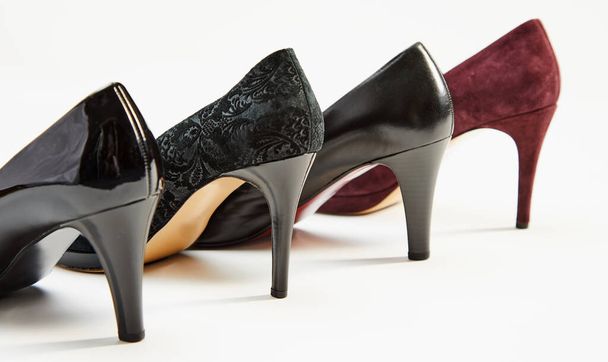 Stiletto heels on a row of elegant black and maroon leather ladies shoes arranged diagonally on white with copy space - Photo, Image