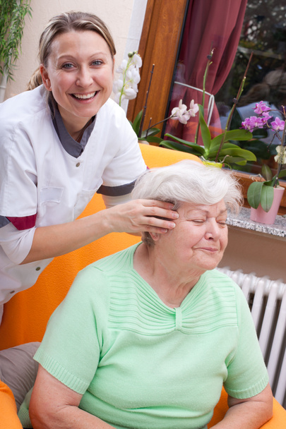 Nurse massages the head of a senior - Foto, imagen