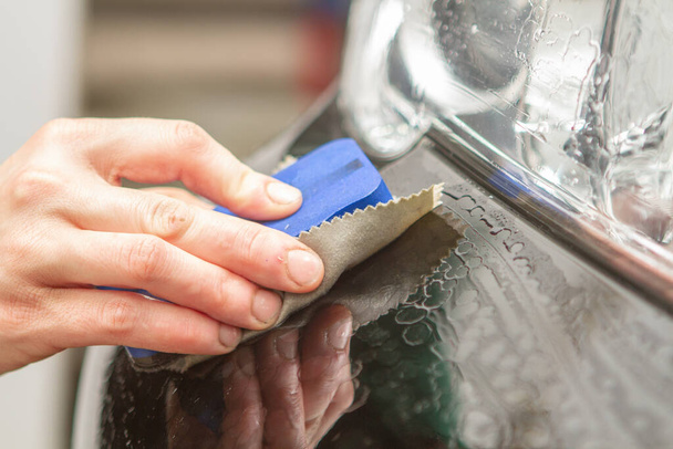 An employee of the car wash thoroughly washes conducts detaling  - Zdjęcie, obraz